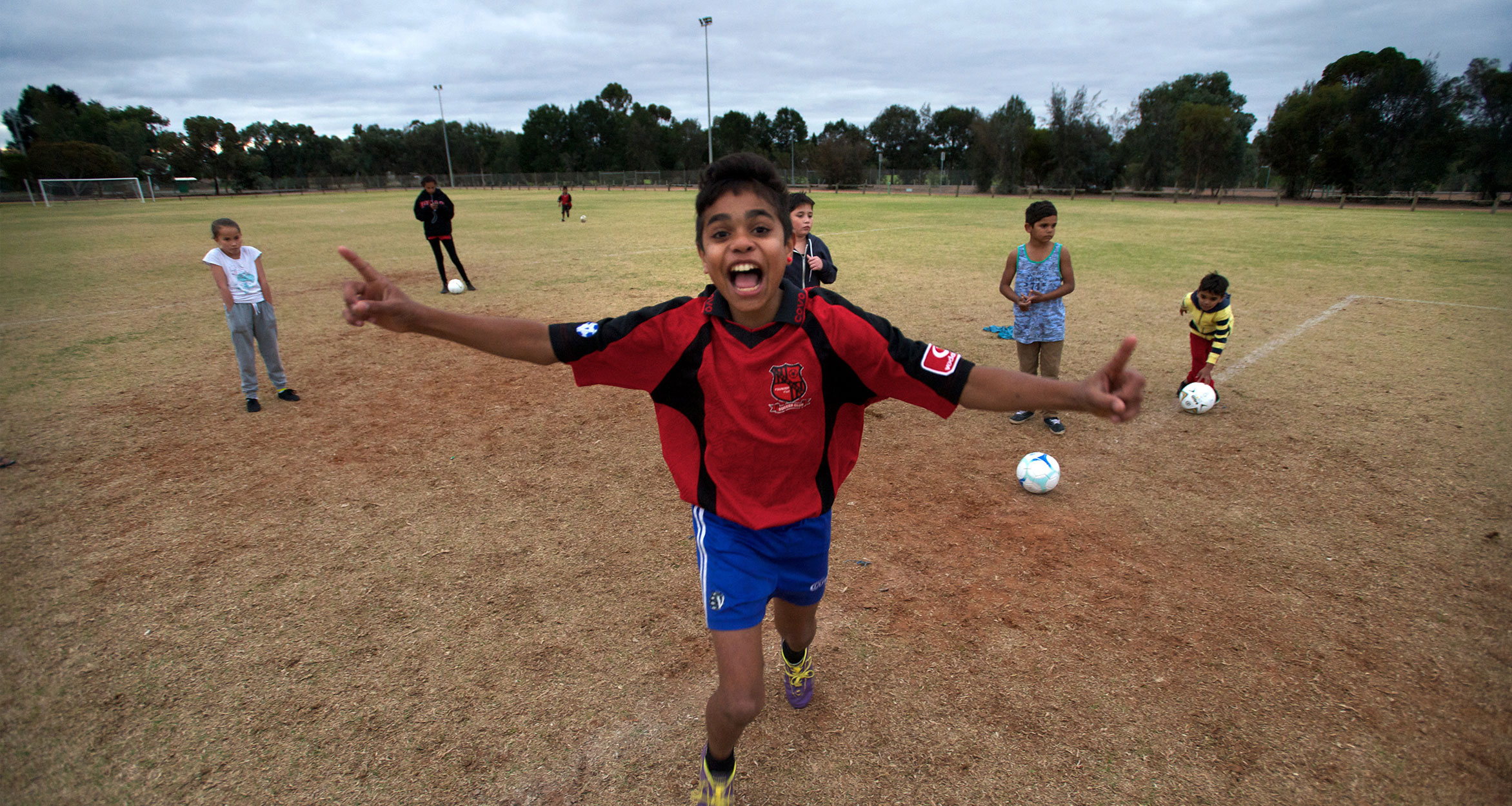 Kids on soccer field kicking goals